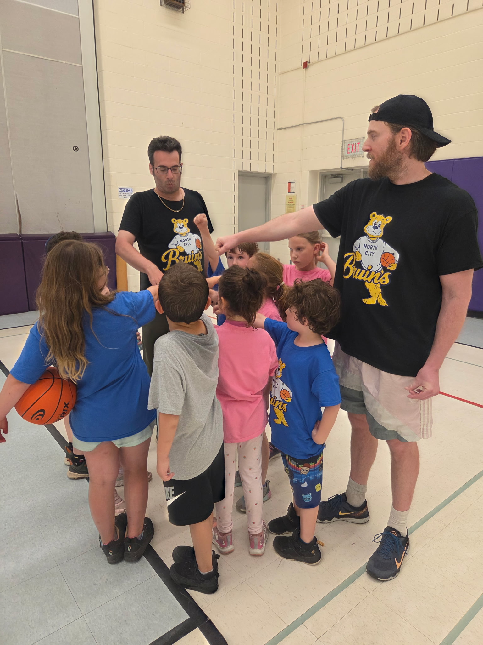 North City Bruins coaches leading a youth basketball group huddle